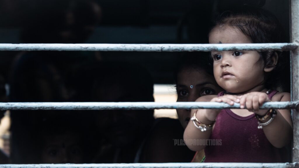 A little girl looks out the train window whilst her mother sits behind her. Indian train carriages are usually always full of family members travelling from one state to the
next.
